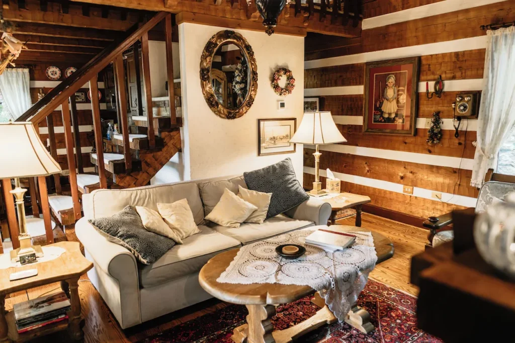 A rustic living room with a beige sofa, wooden coffee table, and an open timber staircase