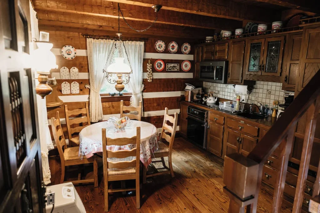 A rustic cabin kitchen with wooden cabinets, a round dining table, and four wooden chairs