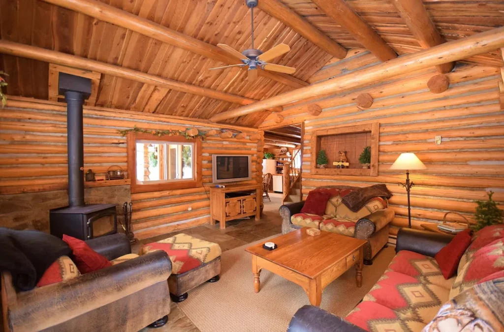Cozy log cabin living room with a wood stove fireplace and pattern sofas
