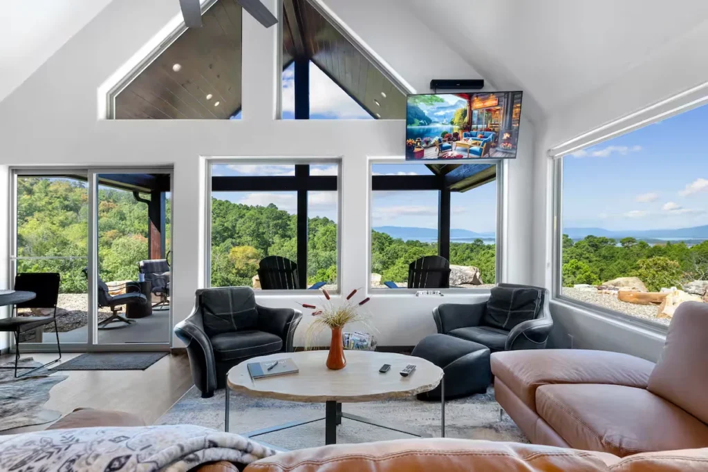 Bright modern cabin living room with large windows overlooking a scenic mountain and lake view