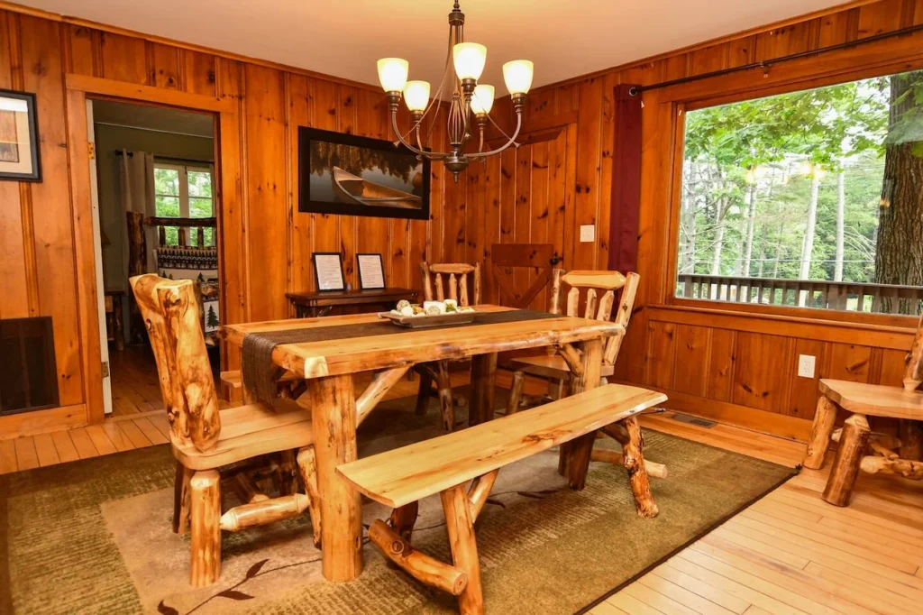 Rustic cabin dining room with a log table, wooden bench, and knotty pine walls