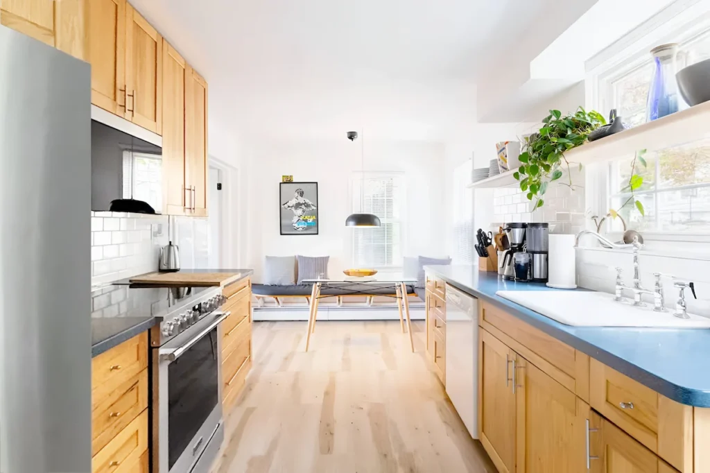 Bright cabin kitchen with light wood cabinets, blue countertops, and an open dining area
