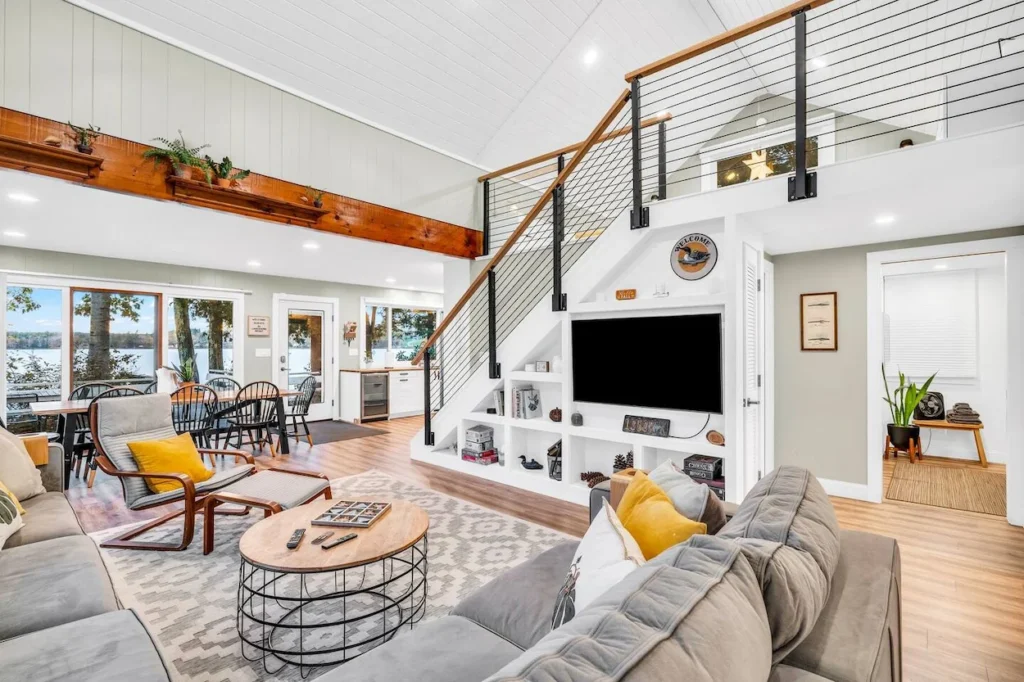 Cabin living room with a loft staircase, built-in media console, and a large gray sectional