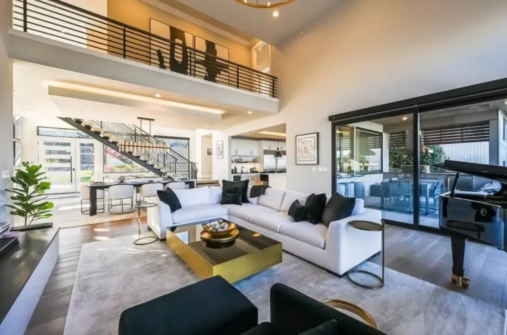 Living room with huge sectional couch and extra seating, a Steinway piano, and tall ceilings