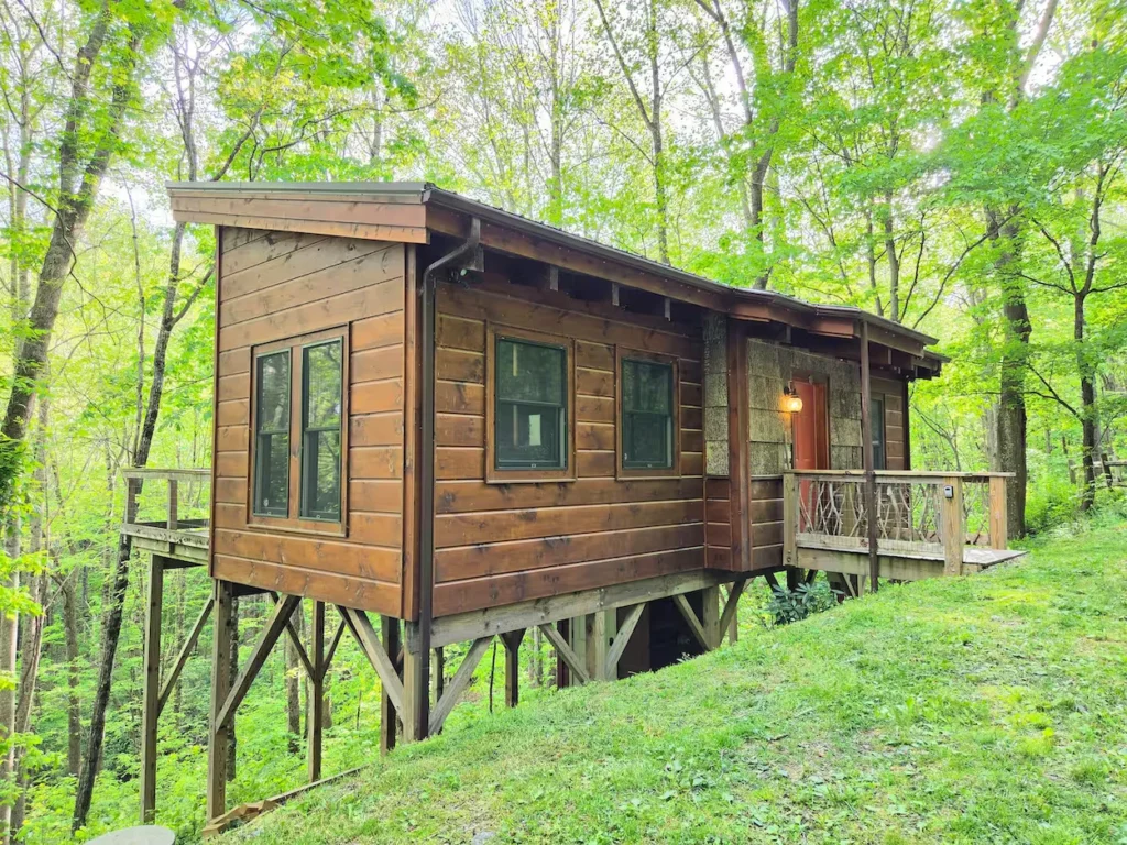 Acorn Acre tiny wooden cabin built on high wooden stilts on a grassy slope in Boone, North Carolina