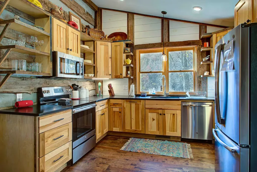 Rustic cabin kitchen with wood cabinets, black counters, and stainless steel appliances