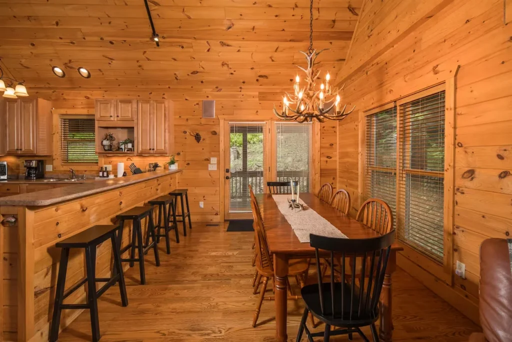 Cabin dining table with an antler chandelier and counter stools