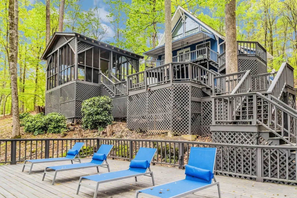 Multi level dark wood deck on a lake cabin with blue lounge chairs