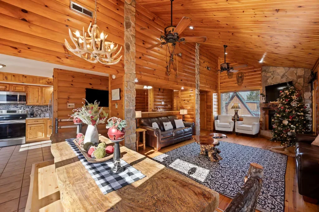 Rustic log cabin interior with wooden walls, leather sofas, and stone accents