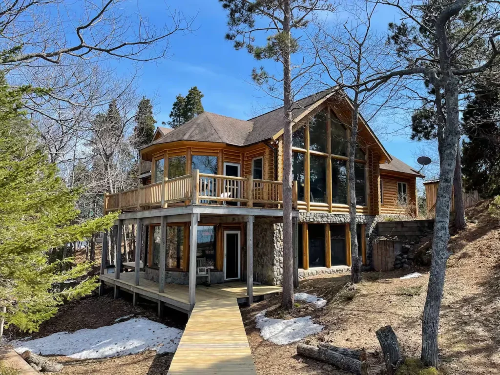 Two-story log cabin with a wooden deck and boardwalk trail