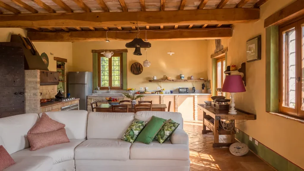 Open concept villa interior with a white sectional sofa, terracotta tile floors, and exposed wood ceiling beams