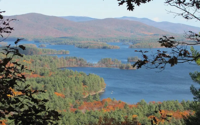 A scenic view of the forested Squam Lakes with mountains in the background.