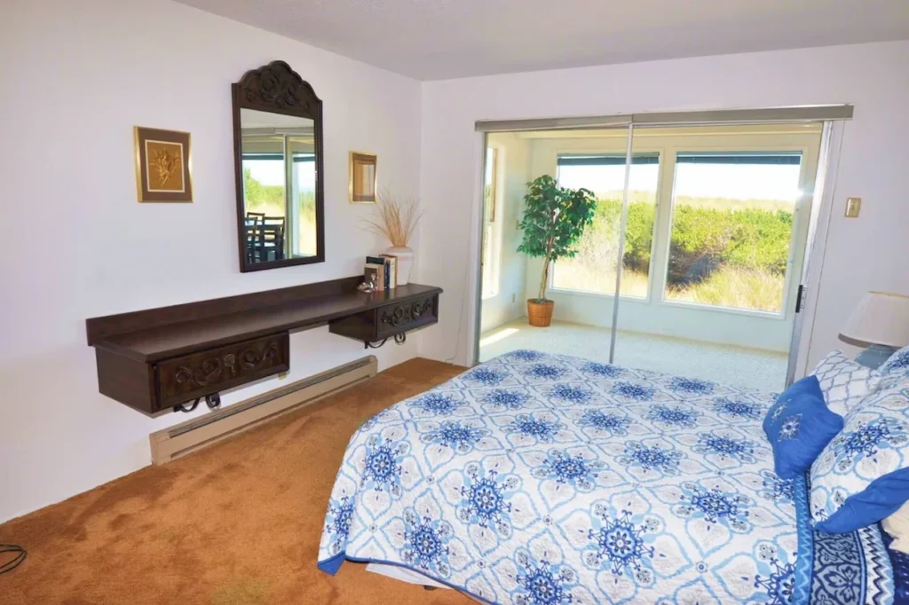 Beach house bedroom with a blue and white patterned bedspread next to sliding glass doors