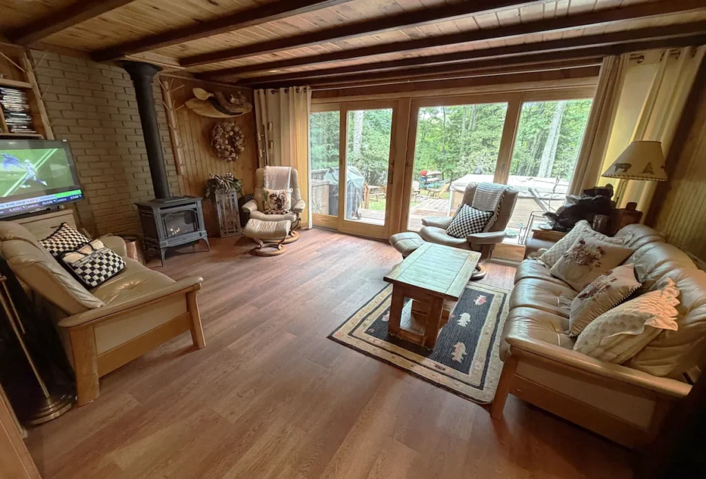 Rustic cabin living room with leather sofas, a wood-burning stove, and large glass sliding doors