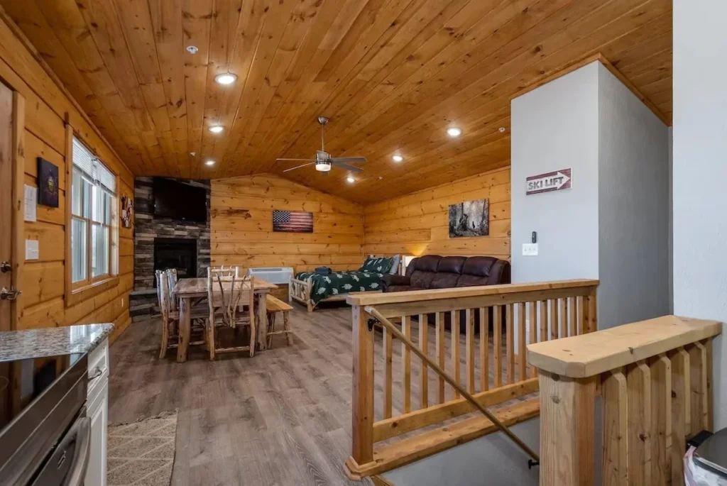 Open studio layout inside a wood paneled mountain cabin with a dining table, couch, and bed