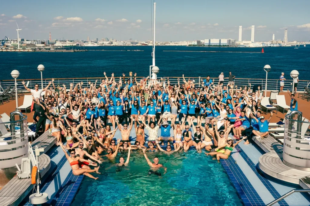 Digital nomads cheering around a cruise ship pool during Nomad Cruise 14 in 2026.