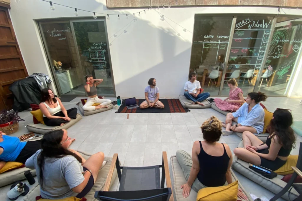 Remote professionals in an outdoor workshop circle on cushions in the Sun and Co. coliving courtyard in 2026