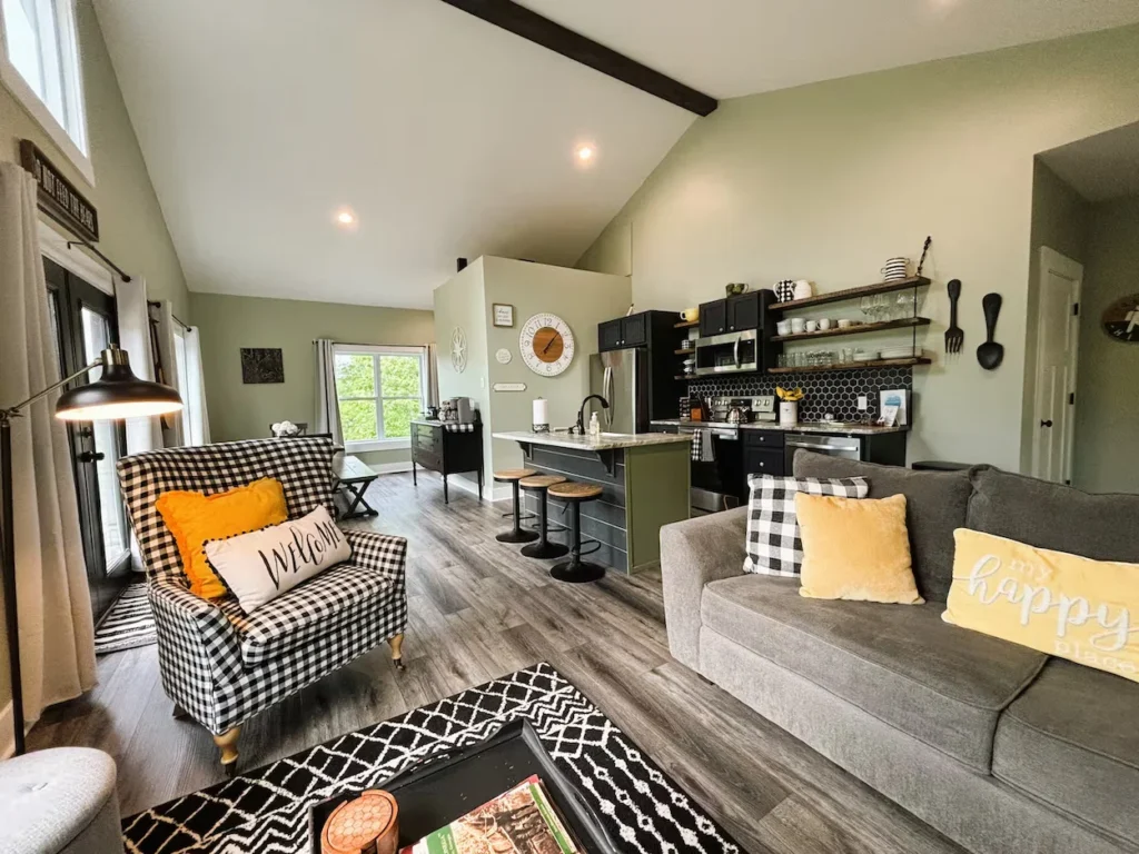 Open cabin living area with a checkered armchair, gray sofa, and kitchen island