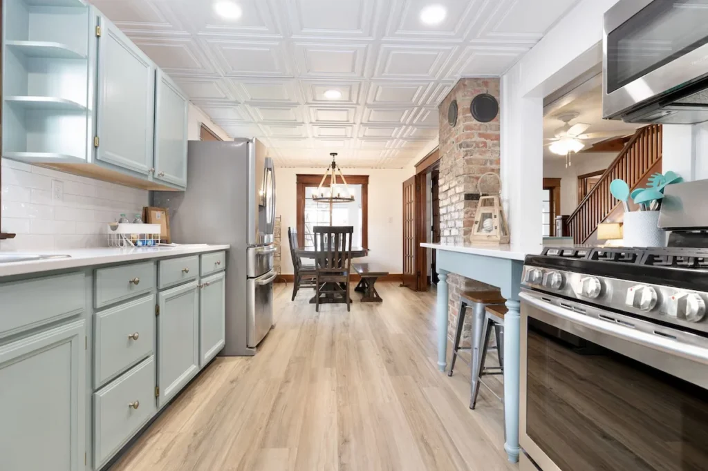 Modern cottage kitchen with light blue cabinets, stainless steel appliances, a breakfast bar, and an attached dining room area