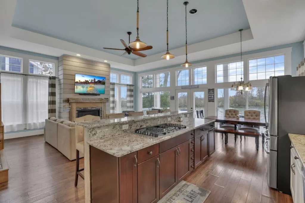 Open concept kitchen with a granite island looking toward a living area and lake windows