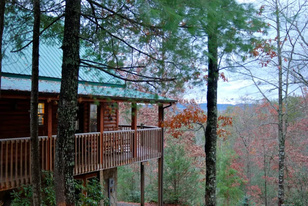 Wooden log cabin deck overlooking a forested mountain landscape with fall foliage