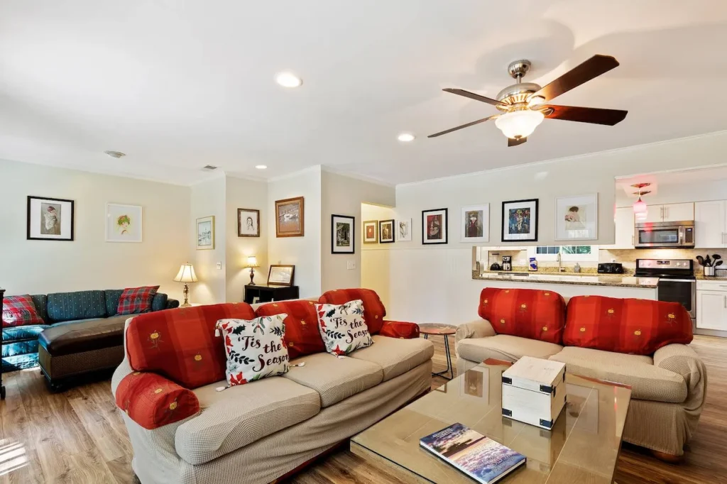 Living room with beige and red patterned sofas, Christmas pillows, and a glass coffee table