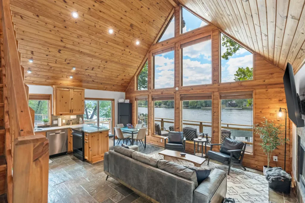 Hot Springs cabin kitchen and living room with tall windows looking at a lake
