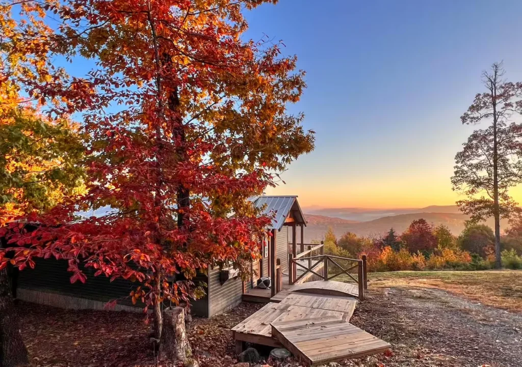 Mountainburg cabin walkway surrounded by vibrant orange fall trees at sunset