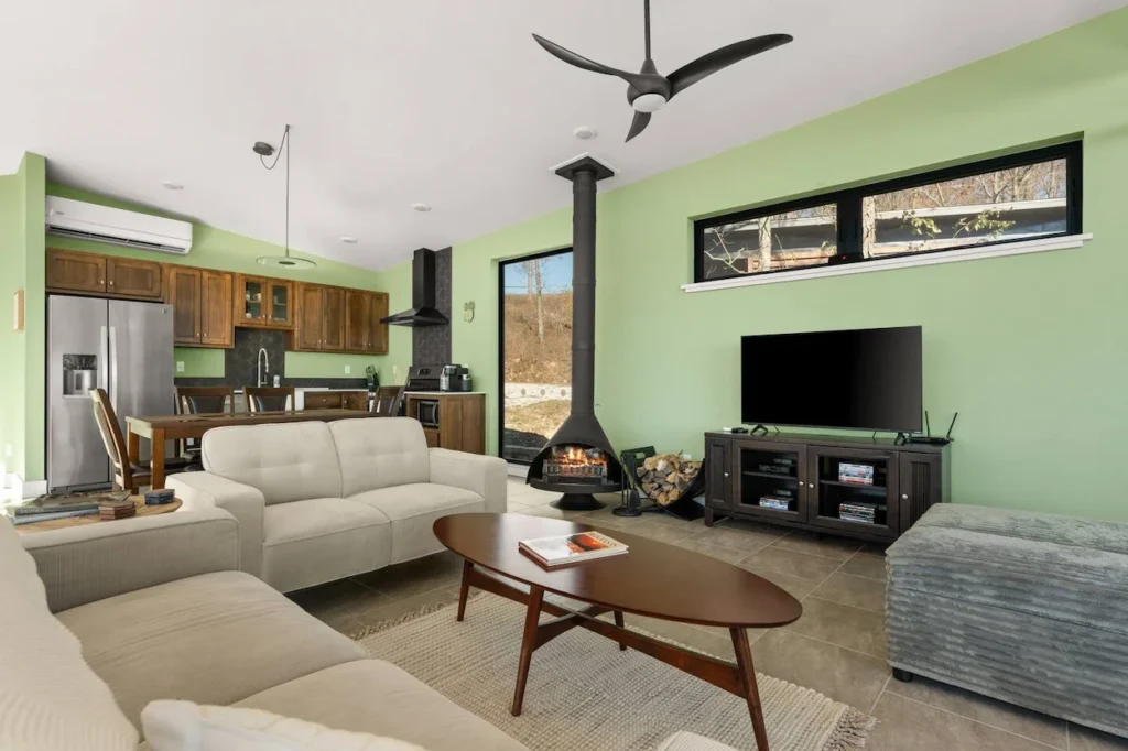 Compton cabin living room with green walls, a black wood stove, and light couches