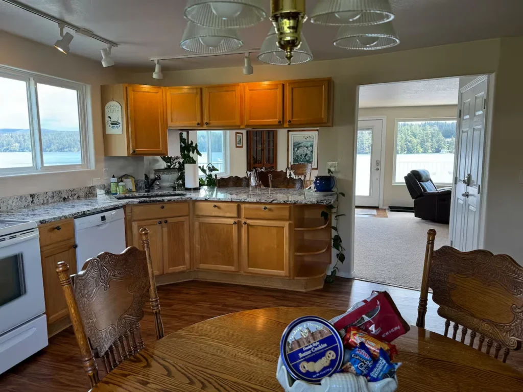 Cabin kitchen with oak cabinets, granite countertops, and a wooden dining table overlooking a lake