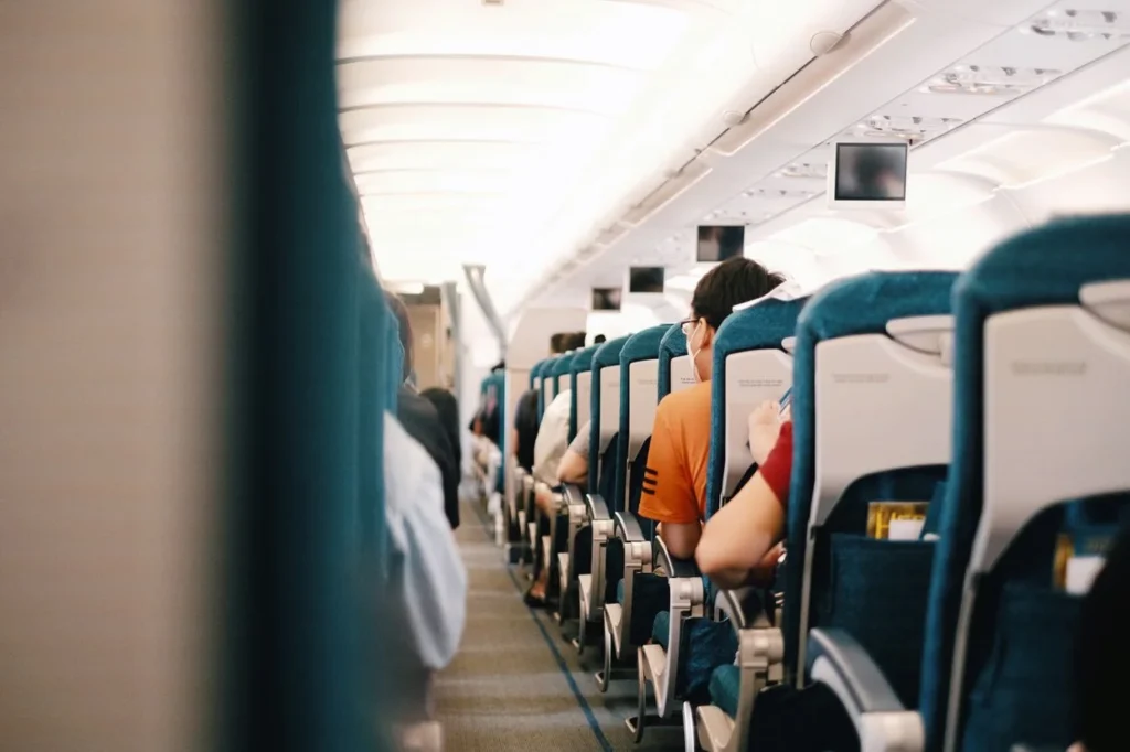 Interior view of an airplane cabin looking down the aisle at seated passengers
