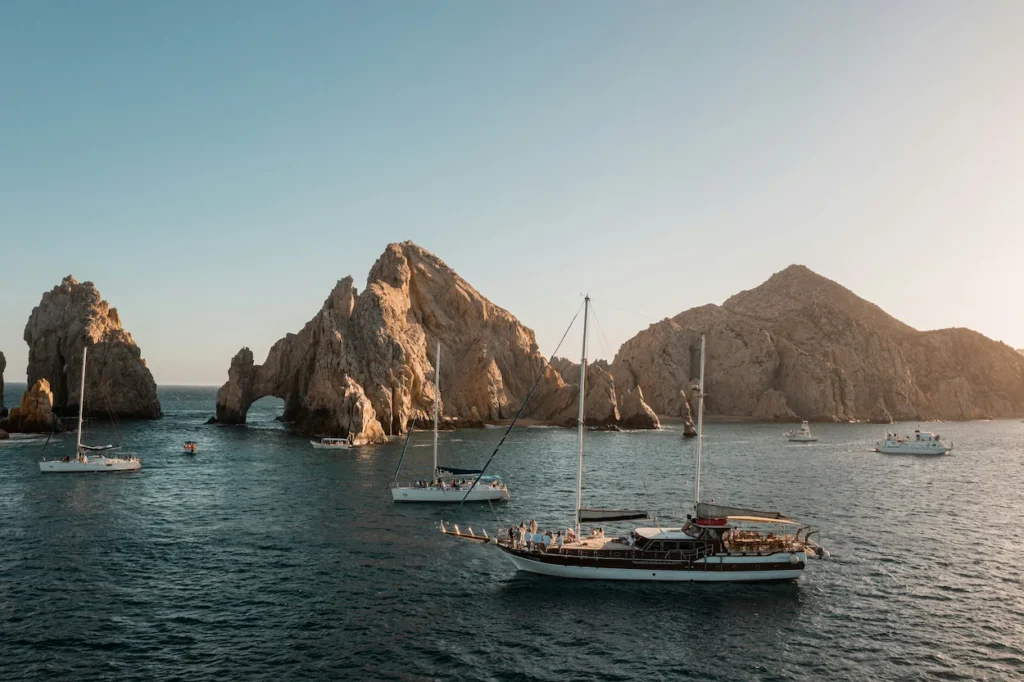Tour boats floating on clear blue water near the Arch of Cabo San Lucas