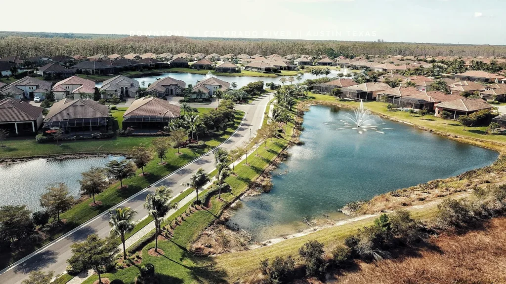 An aerial view of a Florida neighborhood with houses surrounding a pond and fountain