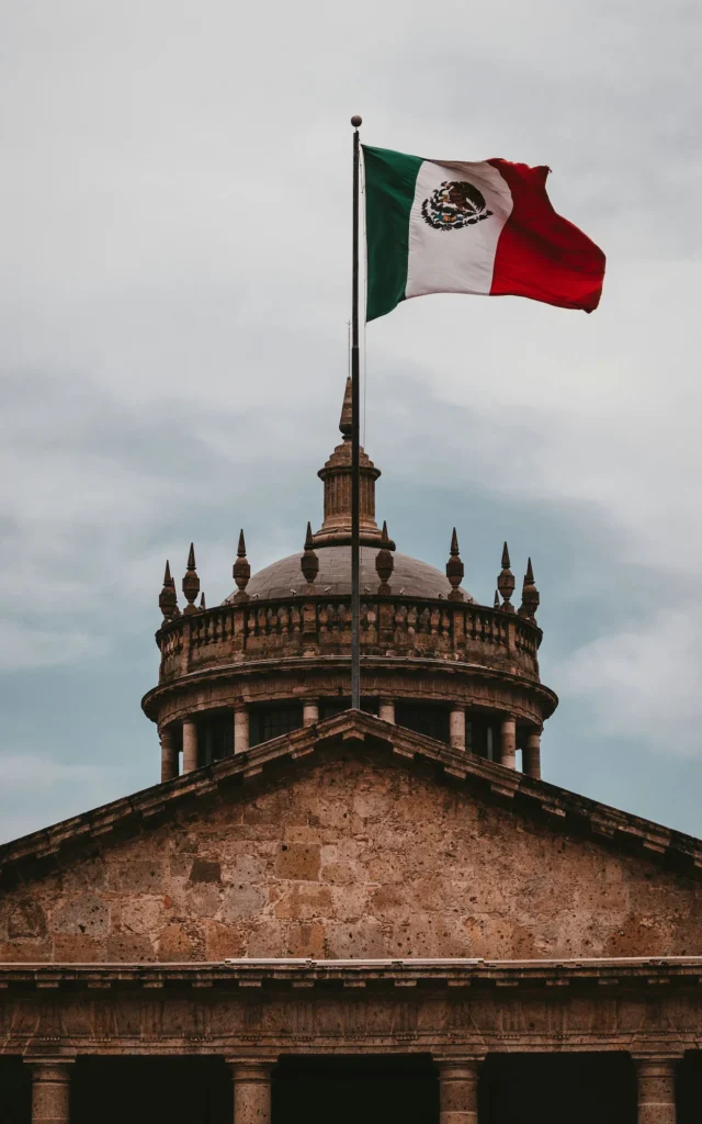 The stone dome of the Hospicio Cabañas building beneath a waving Mexican flag