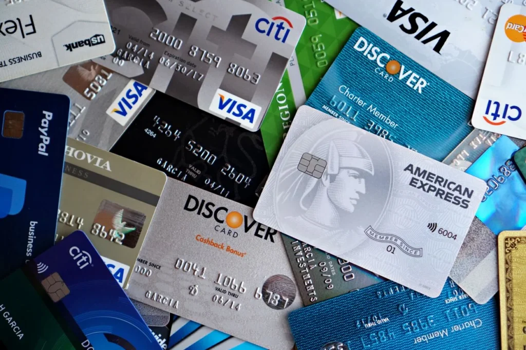 A scattered pile of various credit cards, including American Express, Citi, Visa, and Discover