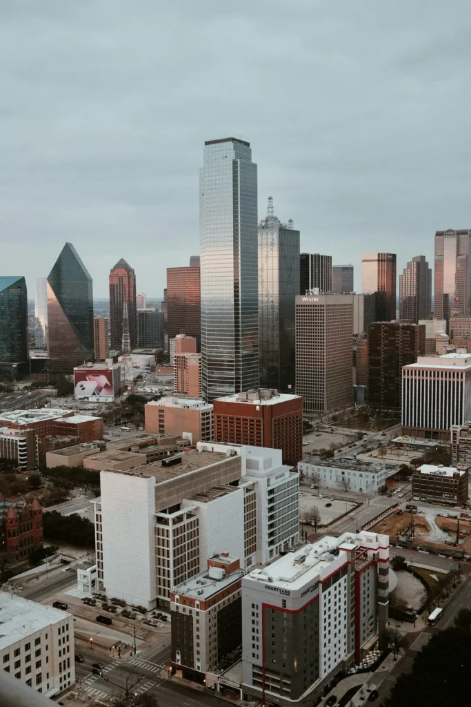 An elevated view of the downtown Dallas city skyline under an overcast sky