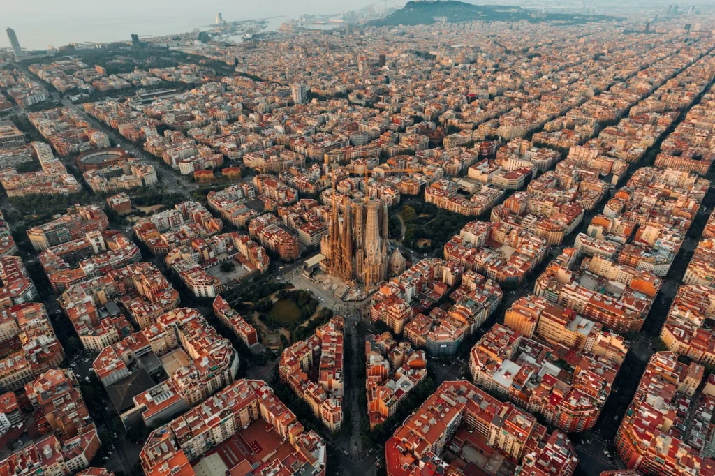 An aerial view of the Sagrada Familia basilica surrounded by the dense city grid of Barcelona, Spain