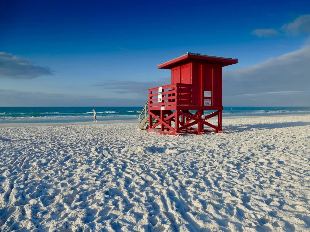 A bright red lifeguard tower on the white sand of Siesta Beach in Sarasota, Florida