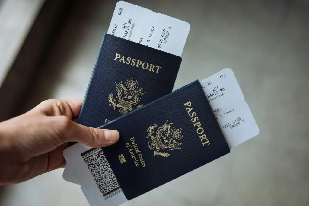A hand holding two US passports and boarding passes
