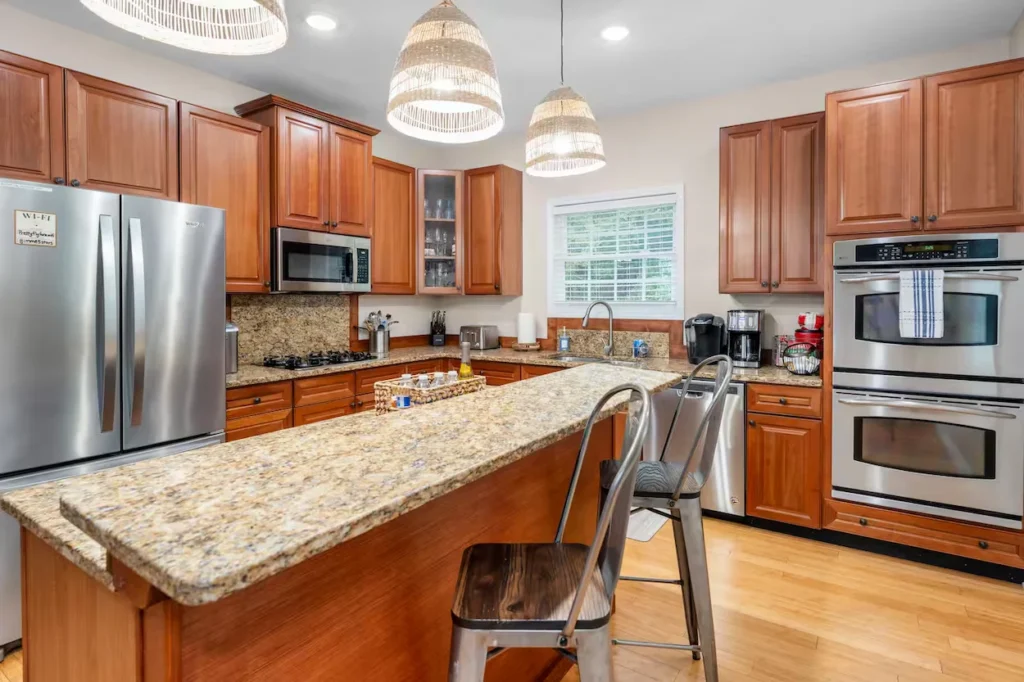 Modern kitchen with wood cabinets, granite countertops, an island with bar stools, and stainless steel appliances