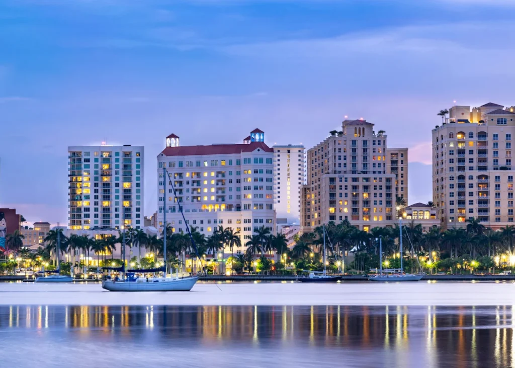 The illuminated West Palm Beach skyline reflecting in the water at twilight