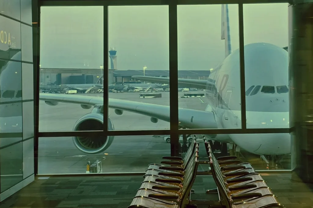 View through a terminal window of a large airplane parked at the gate with airport seating in the foreground