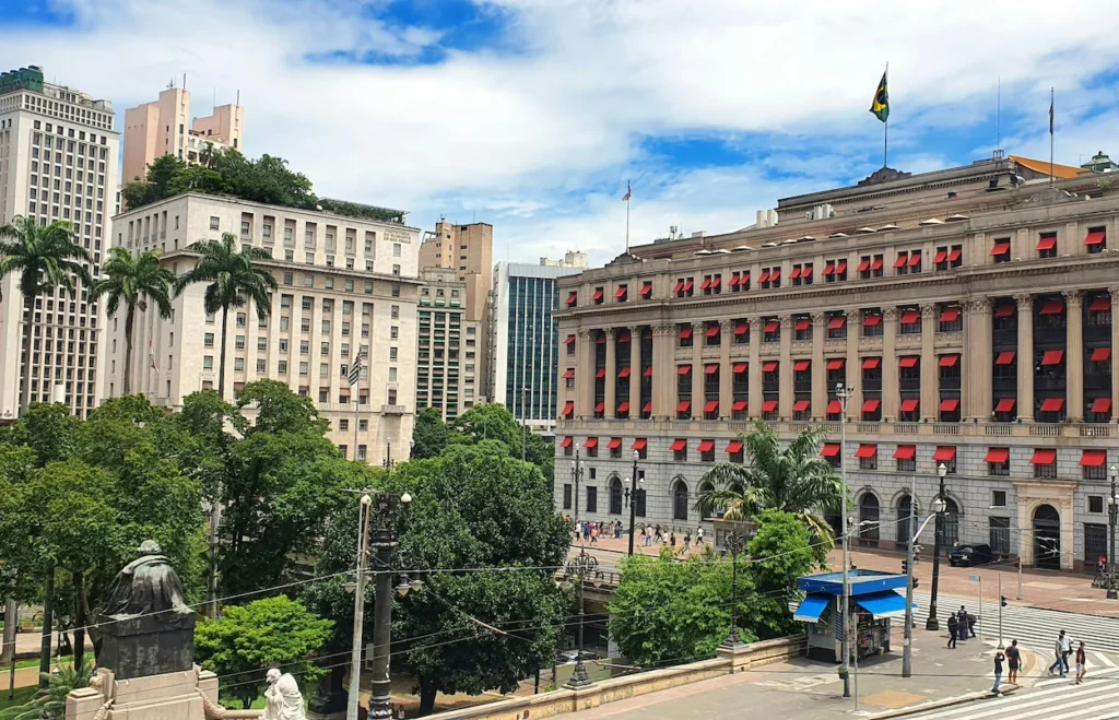Classic stone building with bright red window awnings next to a park in São Paulo