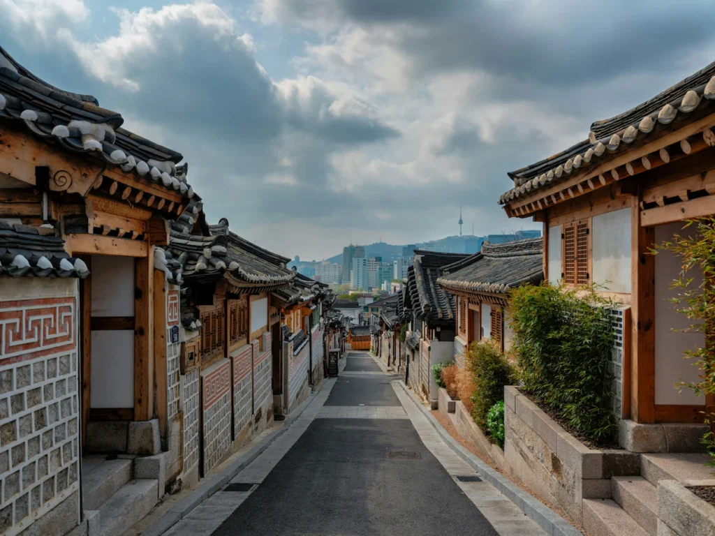 Narrow stone alley lined with traditional Korean hanok houses leading toward N Seoul Tower in the distance