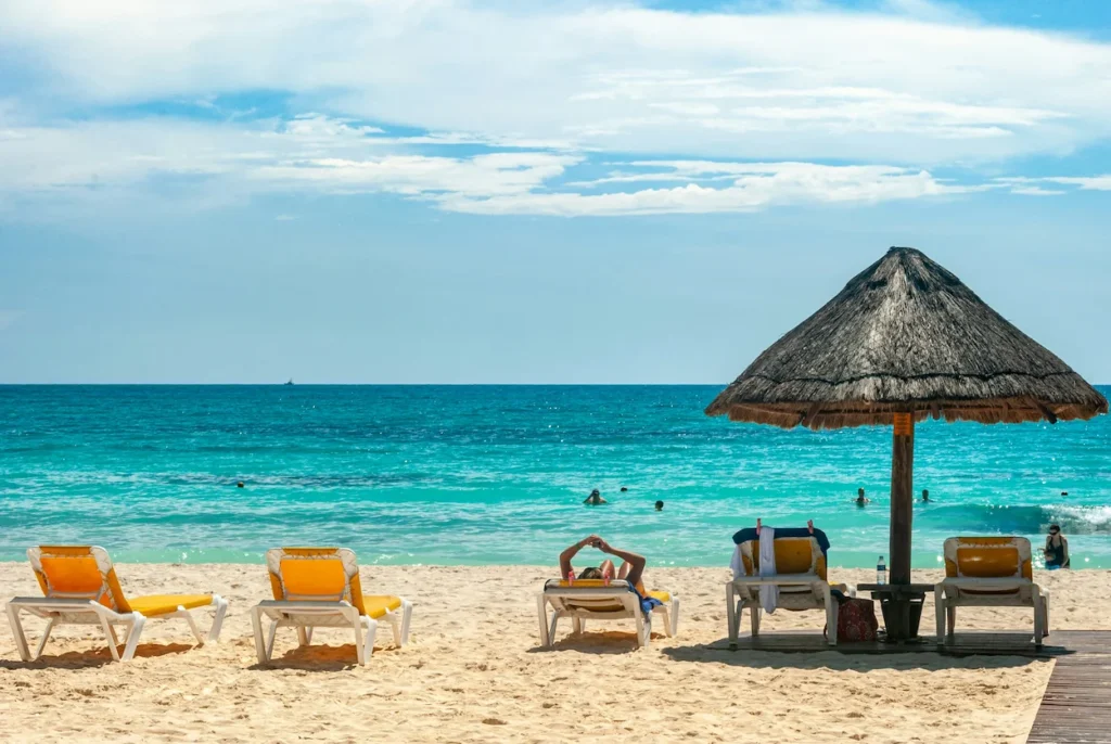Lounge chairs and a palapa umbrella on a sunny turquoise beach