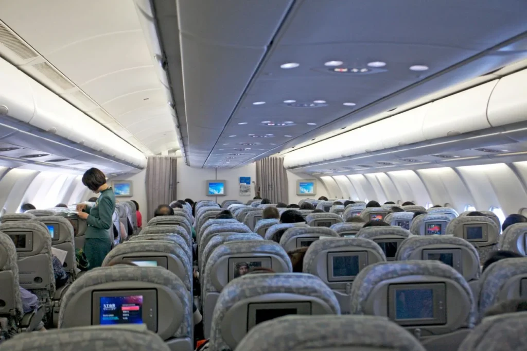The economy class cabin of an EVA Air plane filled with passengers and featuring seatback entertainment screens
