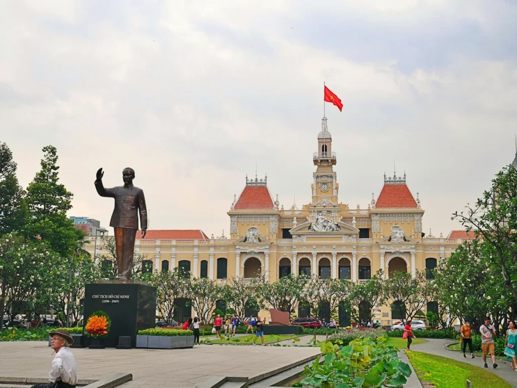 President Ho Chi Minh statue standing in a public square before the yellow Ho Chi Minh City Hall
