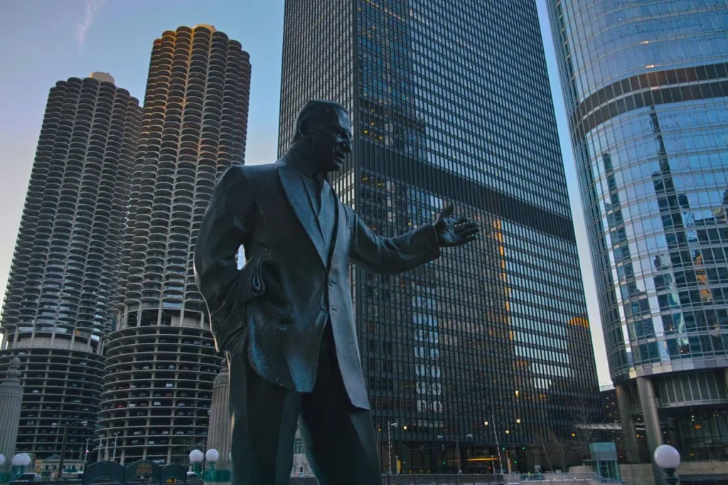 The bronze Irv Kupcinet statue with the Marina City towers and downtown skyscrapers in Chicago