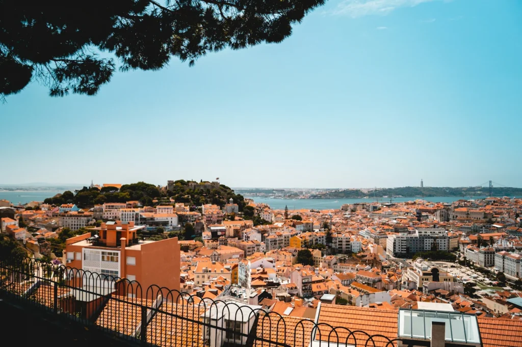 High-angle view of Lisbon rooftops, the Tagus river, and a hilltop castle
