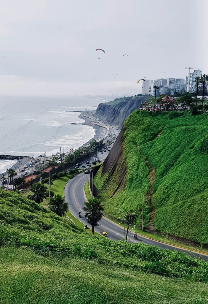 Miraflores cliffs with a winding highway below and paragliders flying above the Lima coastline